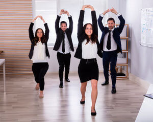 Grupo de jóvenes trabajadores haciendo ejercicio para fomentar un estilo de vida más saludable, una mayor productividad y contribuye a una cultura corporativa positiva y energética